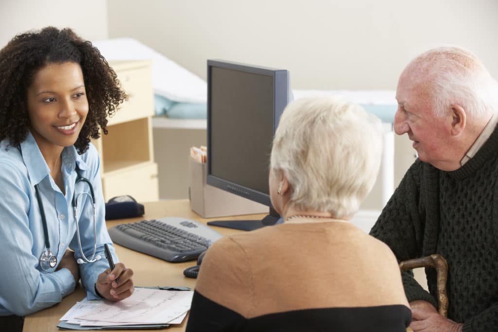 Young female doctor talking to senior couple